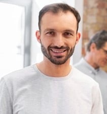 homem sorrindo vestindo camiseta cinza